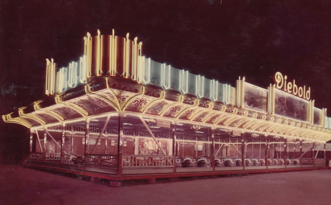 Ein altes Foto der ersten Autoscooter-Anlage der Familie Diebold. Der Autoscooter ist hell erleuchtet und man erkennt den selben Schriftzug mit dem Namen Diebold wie auf dem heutigen Scooter.